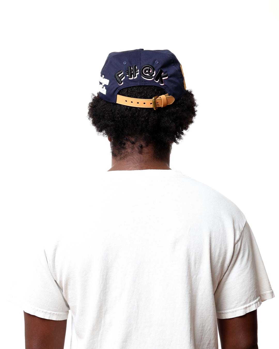 Person wearing a navy blue cap with gold accents on a white background