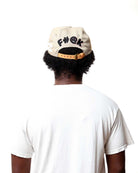 Person wearing a beige cap with black text and a white t-shirt on a white background