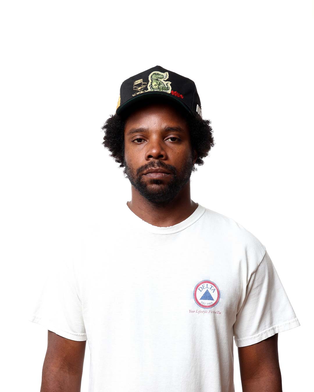 Man wearing a white t-shirt with a logo and a black cap on a white background