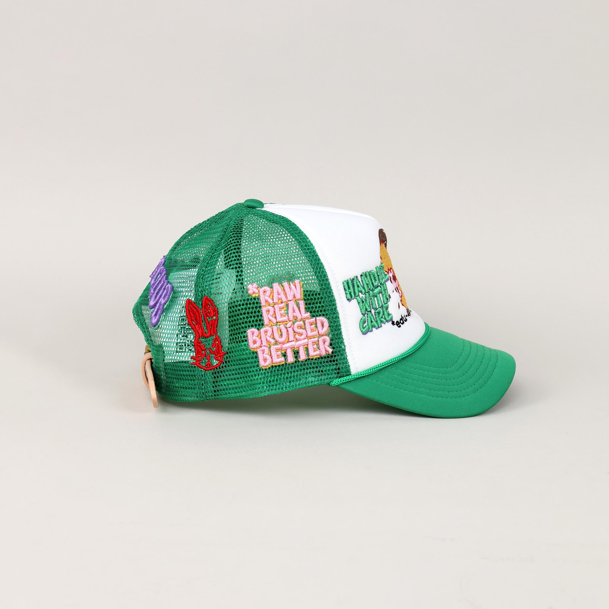 Green and white trucker hat with embroidered patches.