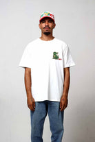 Man in white t-shirt and jeans, wearing a cap.