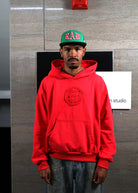 Man in red hoodie and green cap.