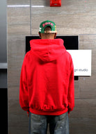 Person in red hoodie facing wall.