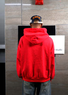 Person in red hoodie facing wall.