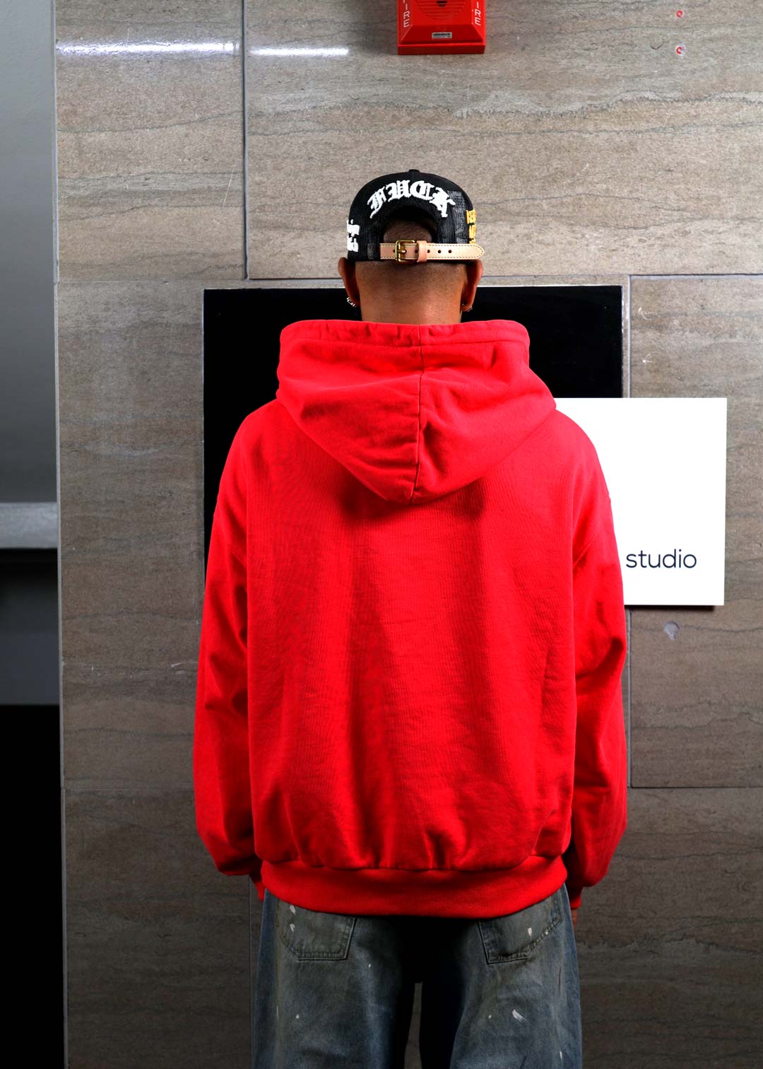 Person in red hoodie facing wall.