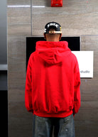 Person in red hoodie facing wall.