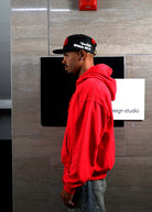 Man in red hoodie and cap, side profile.