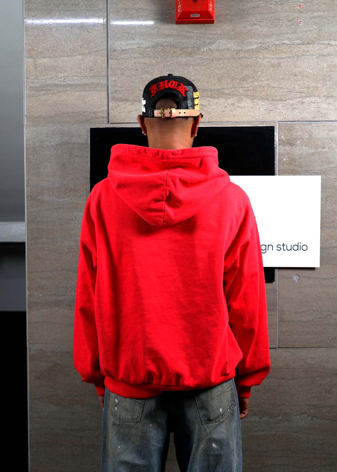 Person in red hoodie facing wall.