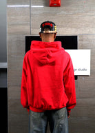 Person in red hoodie facing wall.