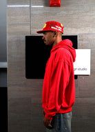 Man in red hoodie and cap, side profile.