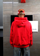 Person in red hoodie facing wall.