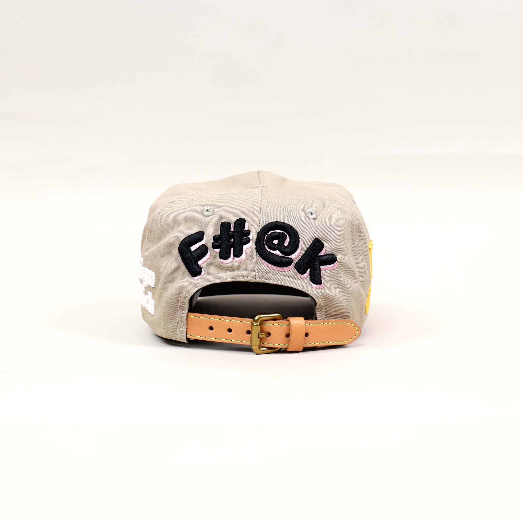 Back view of a beige cap with embroidered text.