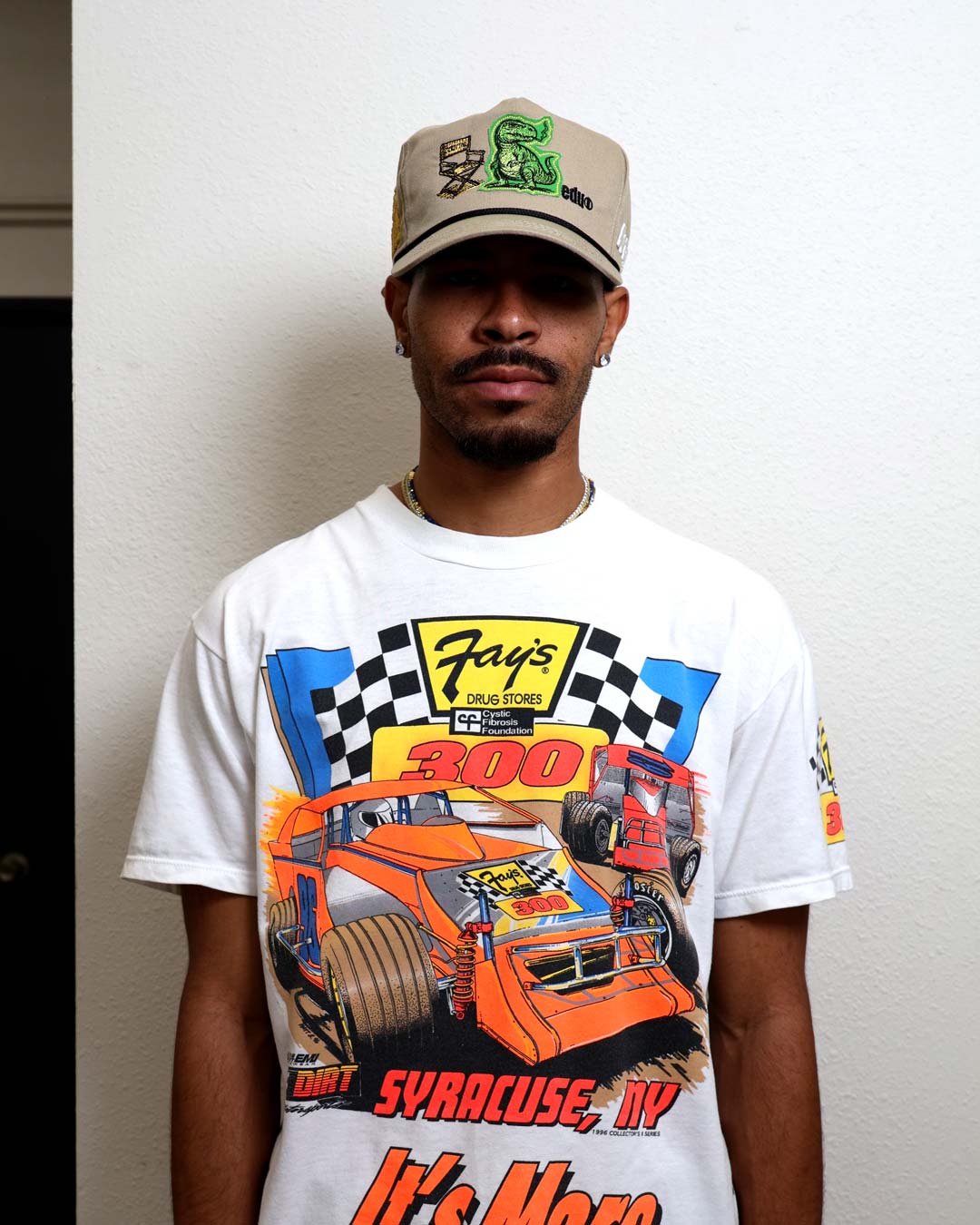 Man wearing graphic racing shirt and cap.