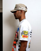 Man in graphic t-shirt and beige cap.