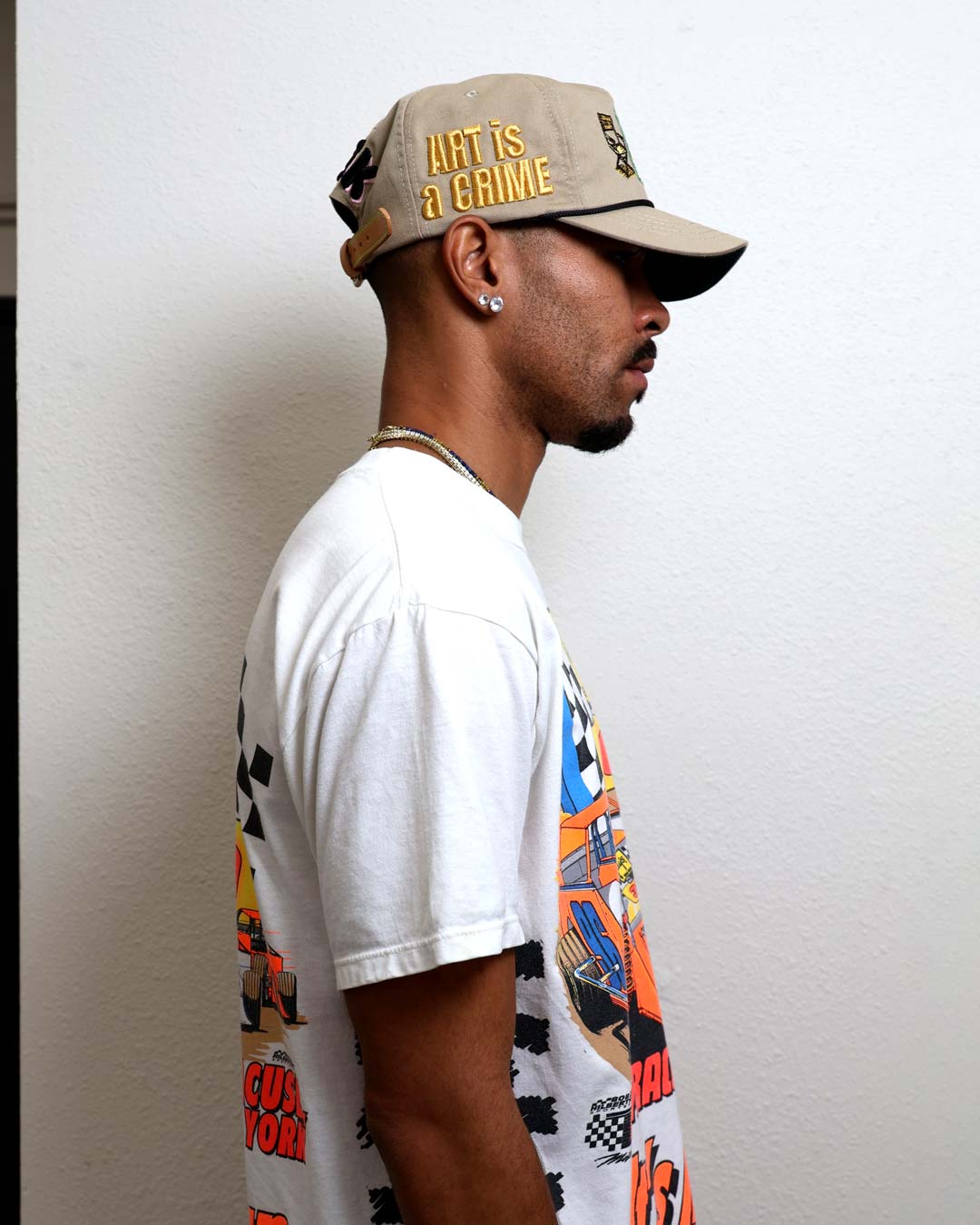 Man in graphic tee and cap facing sideways.