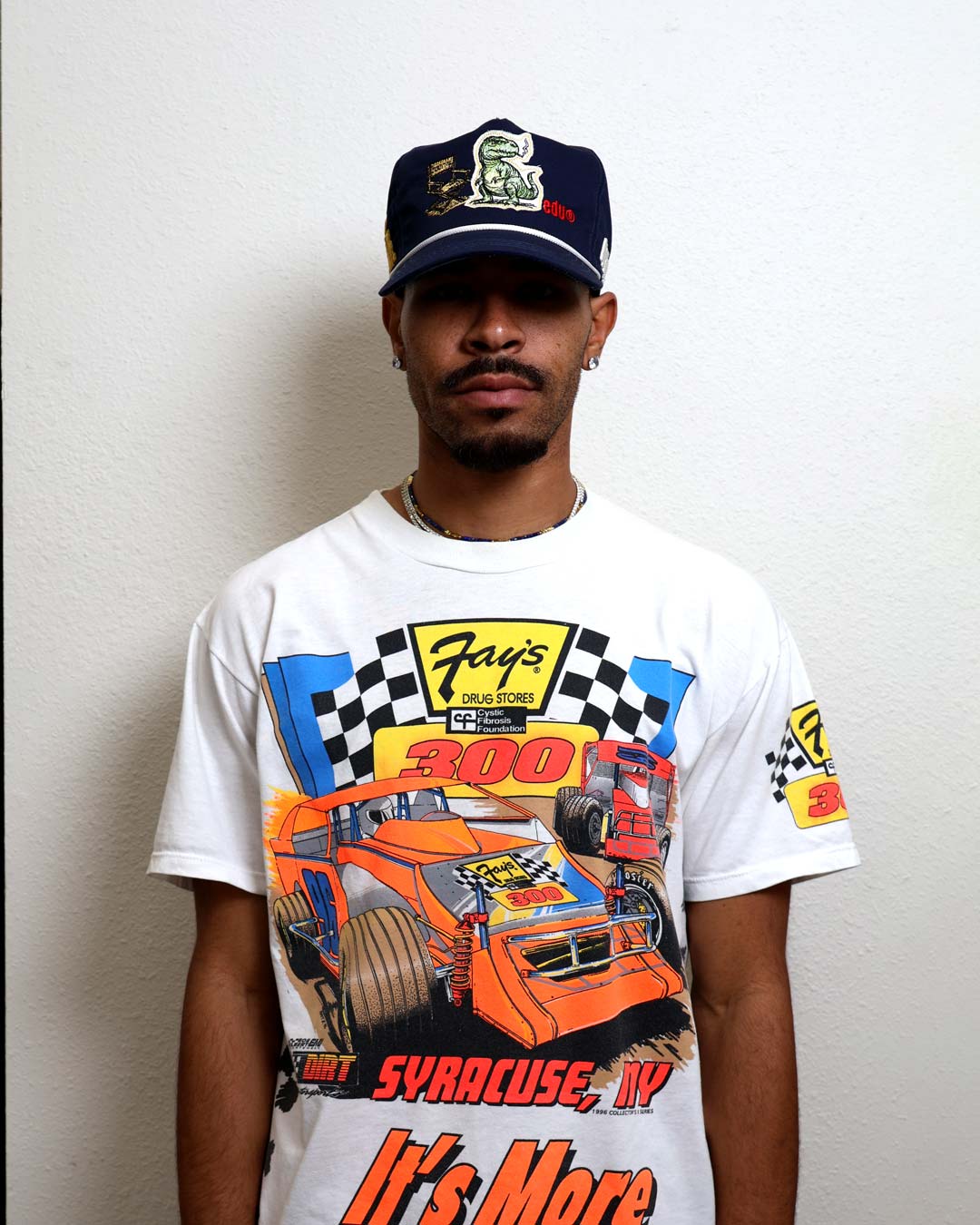 Man wearing racing-themed shirt and cap.