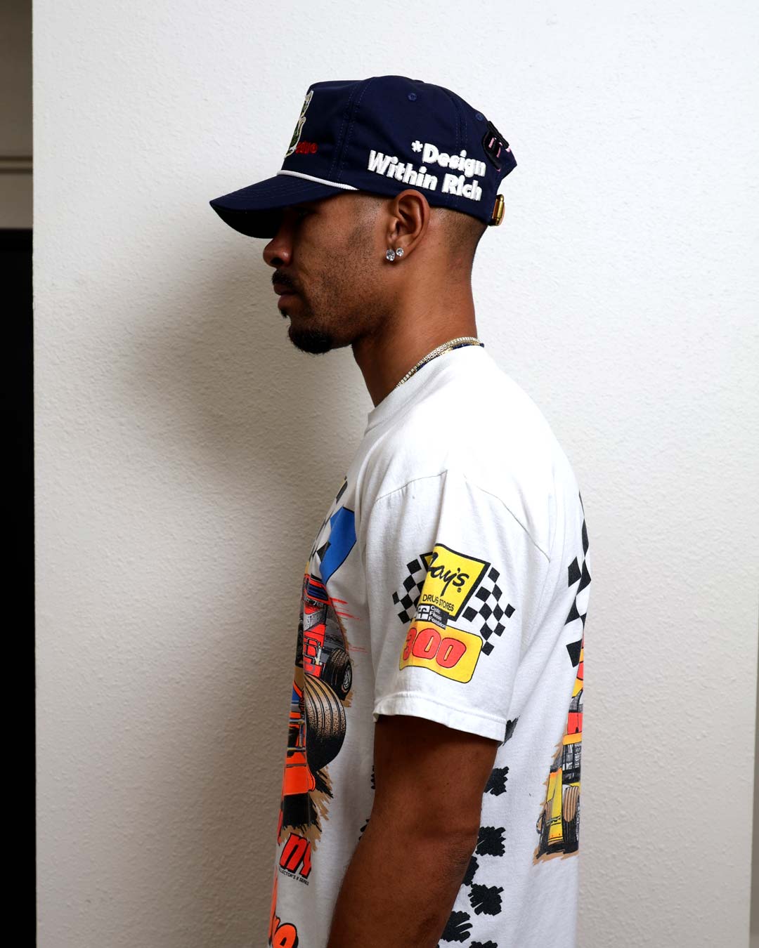 Man in graphic t-shirt and cap, side view.