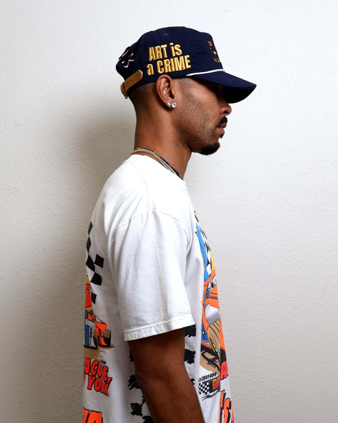 Man in graphic tee and cap, side profile.