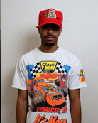 Man wearing racing-themed shirt and red cap.