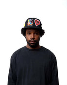 Person wearing a black cap with colorful designs on a white background