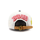 White cap with pink text and brown leather strap on a white background