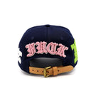 Navy blue cap with pink text and green accents on a white background